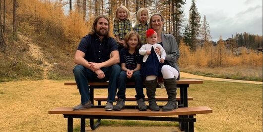 David Stephan his wife Collet Stephan and their frour remaining children sitting on a picnic table in a park.e